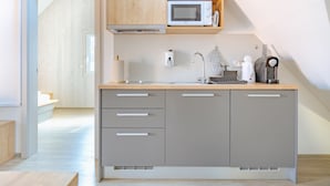 Una cocina moderna con microondas integrado, hervidor y cafetera sobre la encimera.