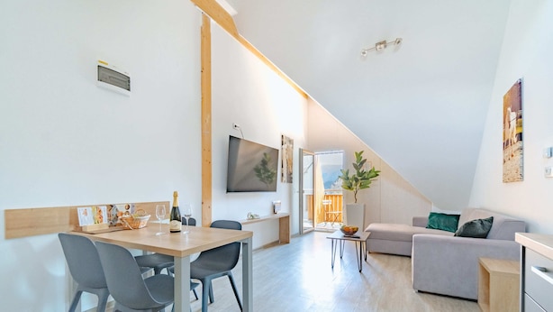 Un espacio habitable moderno con comedor, sofá y una escalera que lleva a un nivel superior.