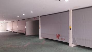 A row of closed hotel rooms with a 'W' logo on the doors, a tiled floor, and a ceiling with recessed lighting.