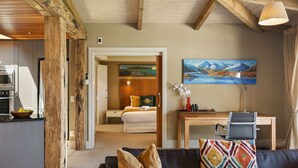 Une chambre d’hôtel avec un lit, un bureau, une chaise, un tableau et une vue sur un paysage montagneux.