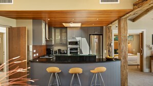 Une cuisine moderne dotée d’un îlot central, de tabourets de bar et donnant sur une chambre.