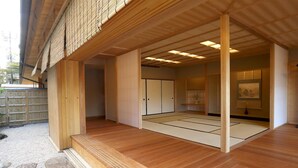 A traditional Japanese room with tatami flooring, sliding doors, and a view of a garden. - Maru Izumiyacho (Kyoto)