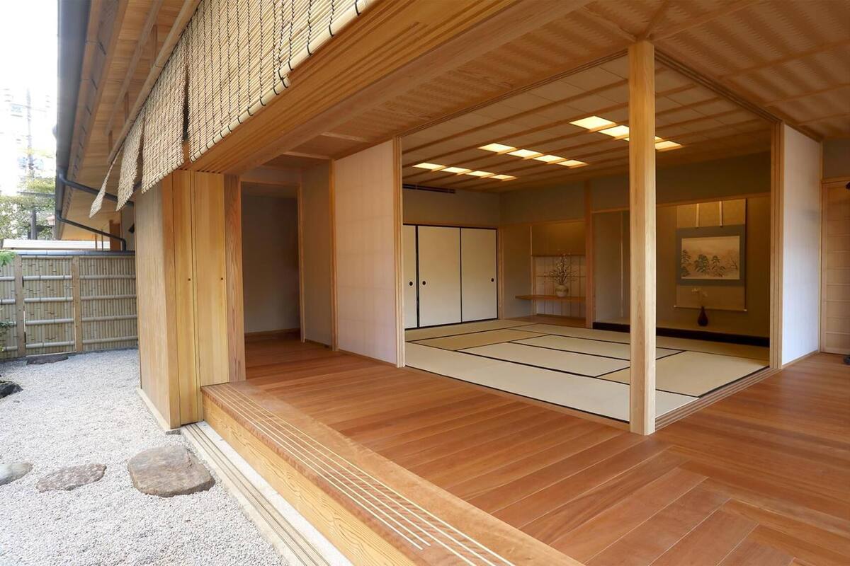 A traditional Japanese room with tatami flooring, sliding doors, and a view of a garden.