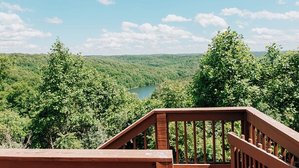 A wooden deck with a view of a lake surrounded by dense forest. - Lake Cumberland Ohana.  Kid friendly, best views, hot tub. (Burnside)