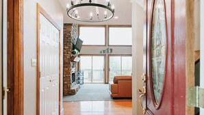A hallway with a wooden floor, a stone fireplace, a television, and a large window. - Lake Cumberland Ohana.  Kid friendly, best views, hot tub. (Burnside)
