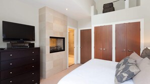 Une chambre avec une télévision, une commode, un grand lit avec des oreillers et une armoire.