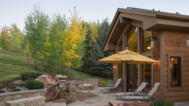 A patio with stone fire pit, outdoor seating, and a large umbrella. - 2 Miles to Downtown Ketchum | Game Room (Sun Valley)