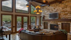 A spacious living room with a stone fireplace, large windows, and a comfortable seating area. - 2 Miles to Downtown Ketchum | Game Room (Sun Valley)