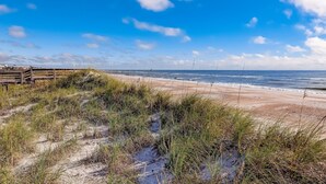 Ein Strand mit Dünen und einem Holzzaun.