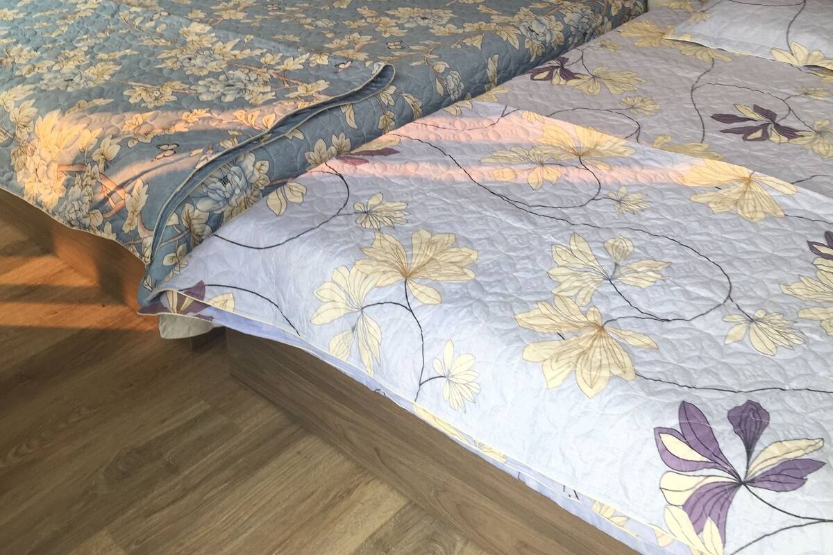 Ein Schlafzimmer mit einem Holz-Kopfteil, einer blumigen Bettdecke und einem Holzboden.