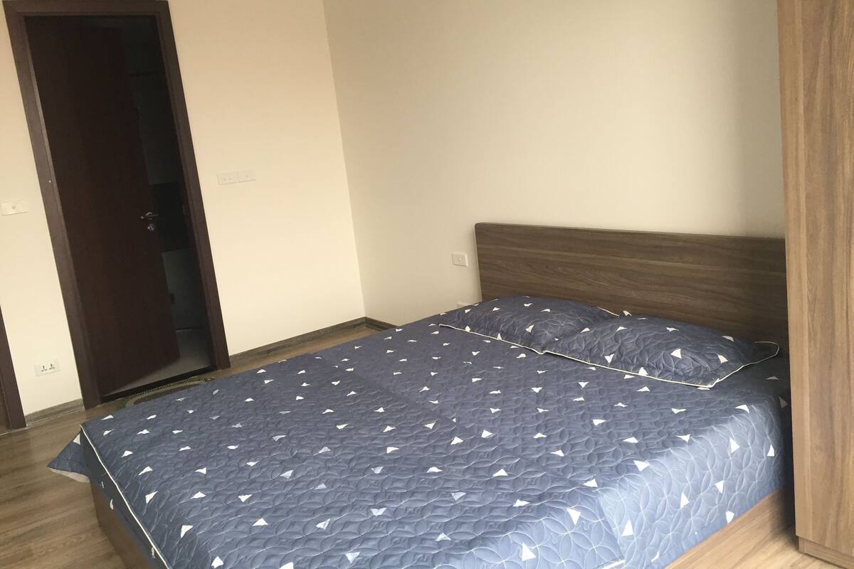 Ein Schlafzimmer mit einem Bett, einem Holz-Kopfteil, einer Tür und einer Wand-Klimaanlage.