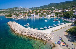 A coastal town with a marina, clear waters, rocky shoreline, and residential buildings. - Holiday apartment mit Balkon und Meerblick (Klenovica)