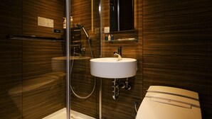 Un baño moderno con ducha de vidrio, lavabo blanco y retrete.
