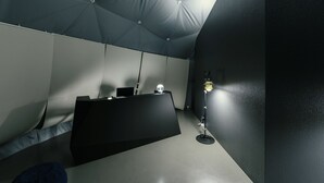 Una habitación con un escritorio negro, una lámpara y una estructura similar a una tienda sobre la cama.