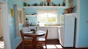A kitchen with wooden cabinets, a white refrigerator, a stove, and a dining table with chairs. - Cozy Cottage Perfect for 2 (Exuma)