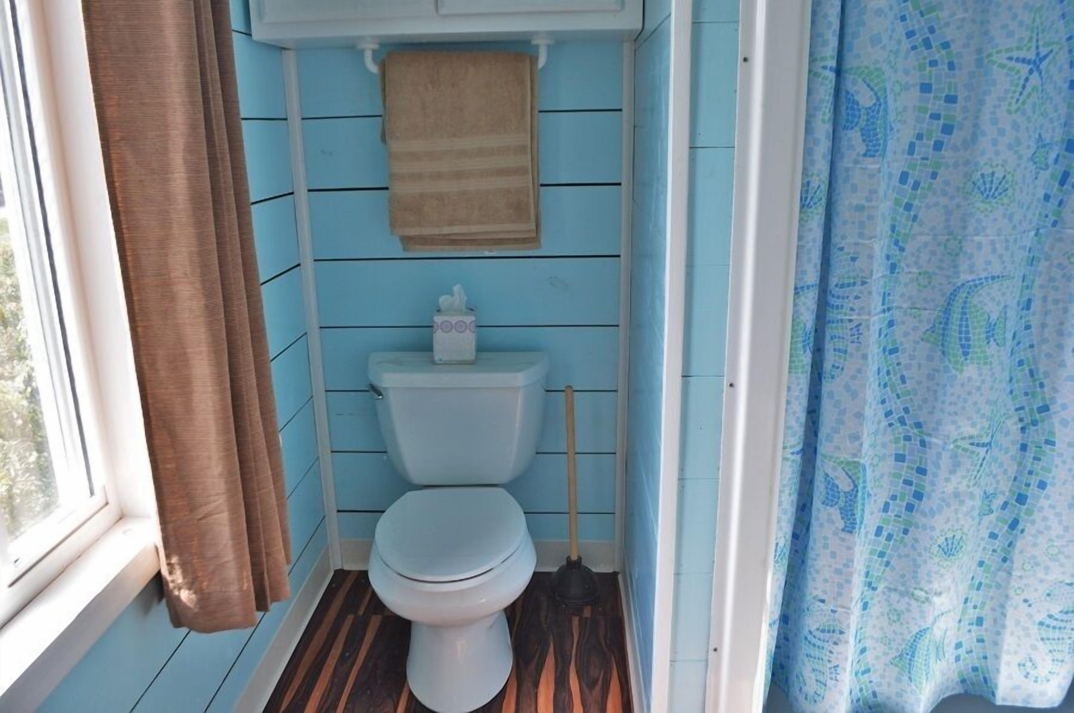 Un baño pequeño con inodoro, una toalla colgada en la pared y cortina de ducha.