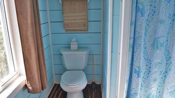 Un baño pequeño con inodoro, una toalla colgada en la pared y cortina de ducha.