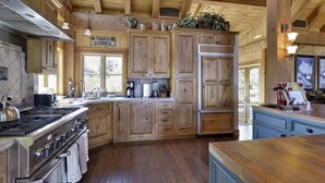 A spacious kitchen with wooden cabinets, a stainless steel stove, and a large island with a sink. - Glacier Luxury Lodge 360 Views (Truckee)