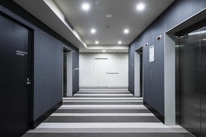 Stylish hallway leads to the elevator, with doors to guest rooms and services nearby.