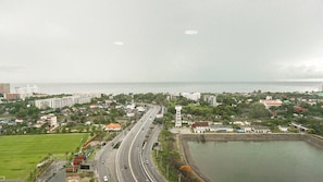 Un paysage urbain côtier avec une autoroute bien visible, un phare et une vaste étendue d’eau.