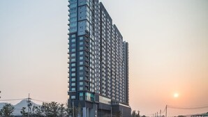 Un grand immeuble moderne, une tour imposante, d’où l’on a une vue dégagée sur le coucher de soleil à l’horizon.