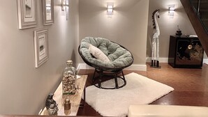 Una sala moderna con un sillón verde, alfombra blanca y cuadros en la pared.