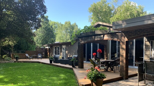 Un patio con mobiliario exterior, un muro de ladrillo y un césped.