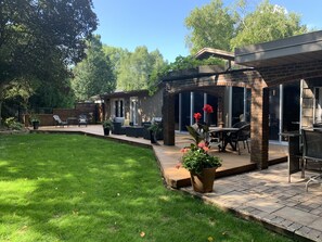 A patio area with outdoor seating, a brick wall, and a grassy lawn. - Silver Birch Suite - Professionally designed Guest Suite (Cambridge)