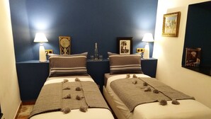 A hotel room with two beds, each with a patterned blanket and pillows, a nightstand with a lamp, and a framed picture on the wall. - Riad Bilkis Votre Maison à Marrakech (Marrakech)