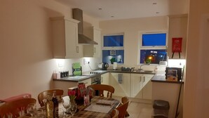 Una cocina moderna con armarios blancos, una isla central y un comedor con mantel a cuadros.