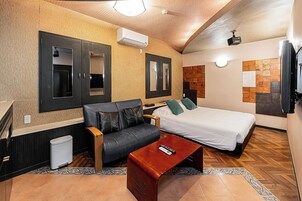 A hotel room with a bed, a sofa, a coffee table, and a TV.