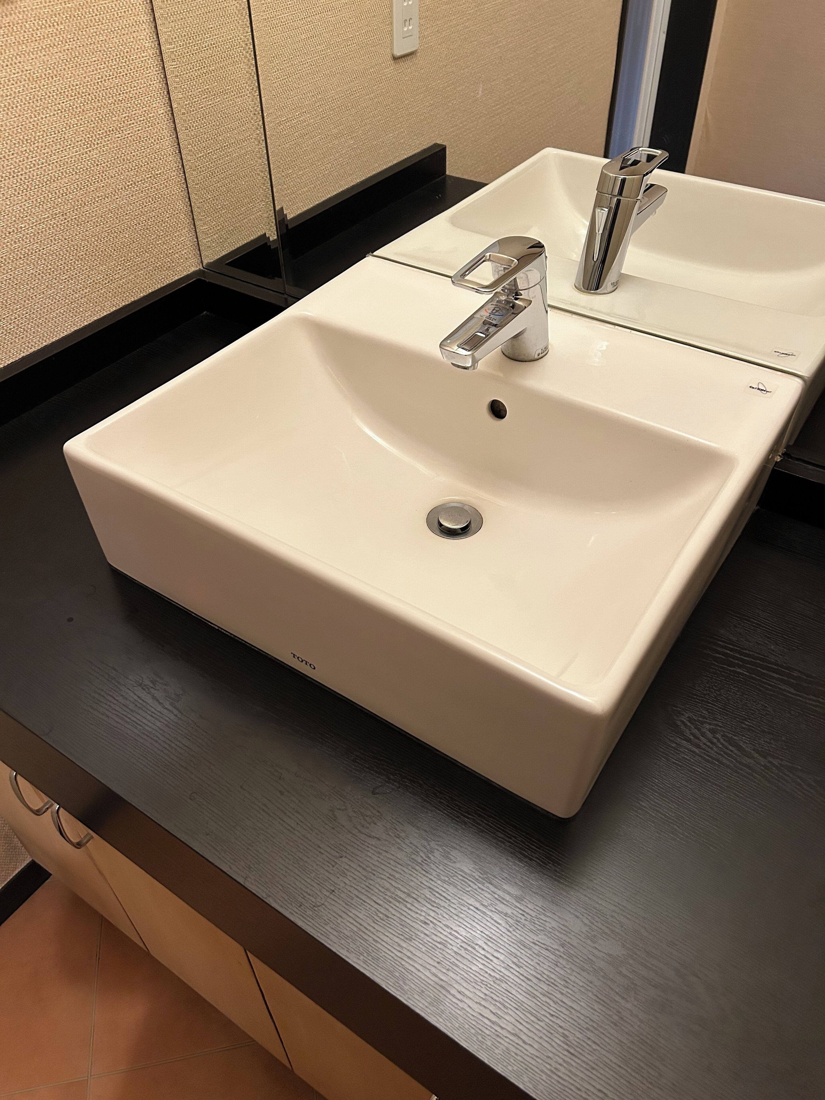 A white bathroom sink with a modern faucet, a mirror above it, and a black countertop.