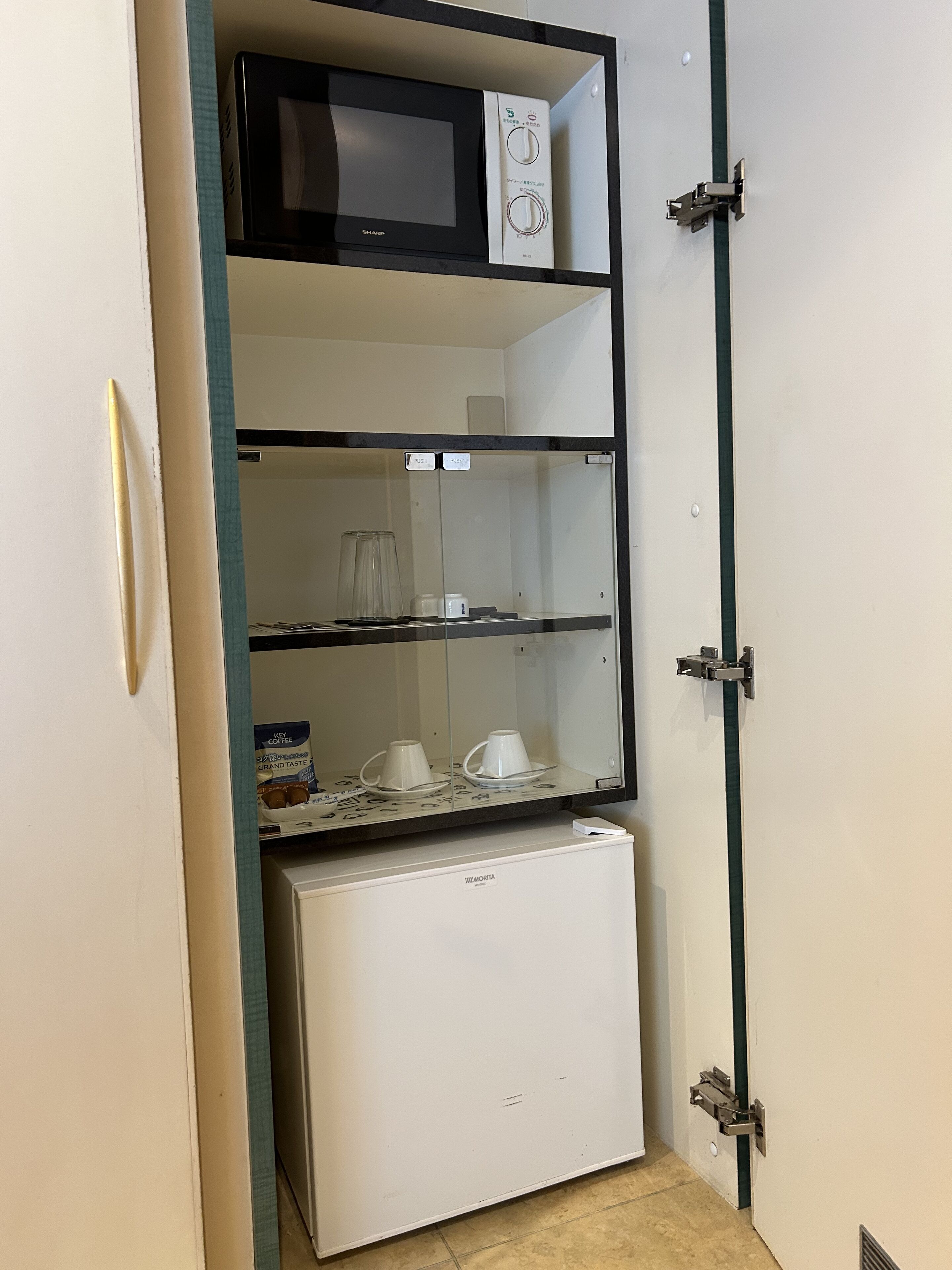 Una kitchenette compacta equipada con microondas, cafetera y refrigerador pequeño.