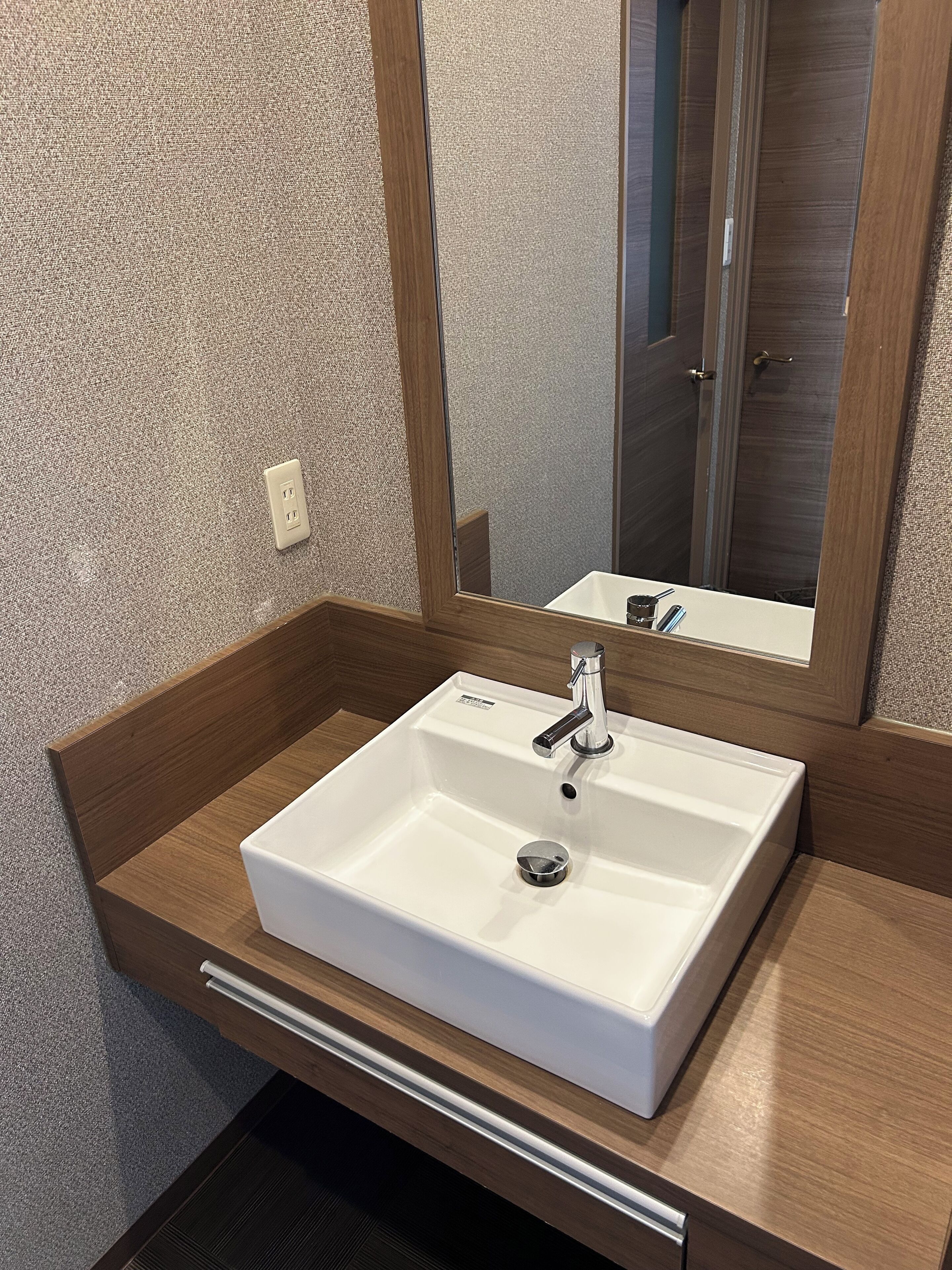 A bathroom with a white sink, wooden countertop, and a mirror.