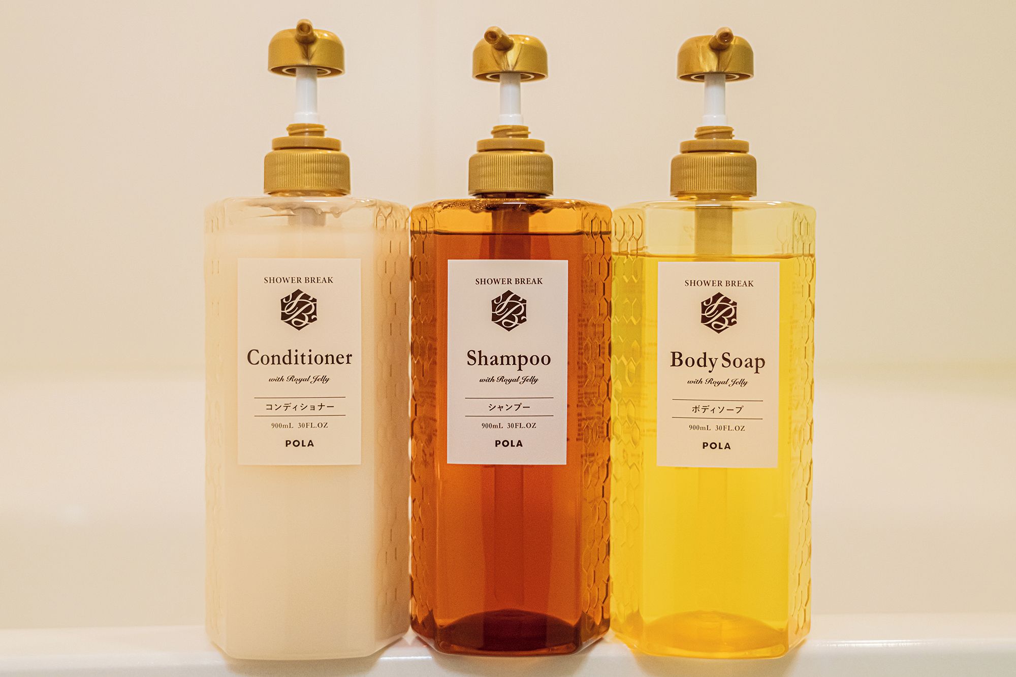 Trois bouteilles de produits pour la douche, toutes munies d’une étiquette et d’un distributeur à pompe.