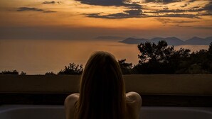 A person sitting in a bathtub overlooking a sunset view. - Faralia Hotel (Fethiye)