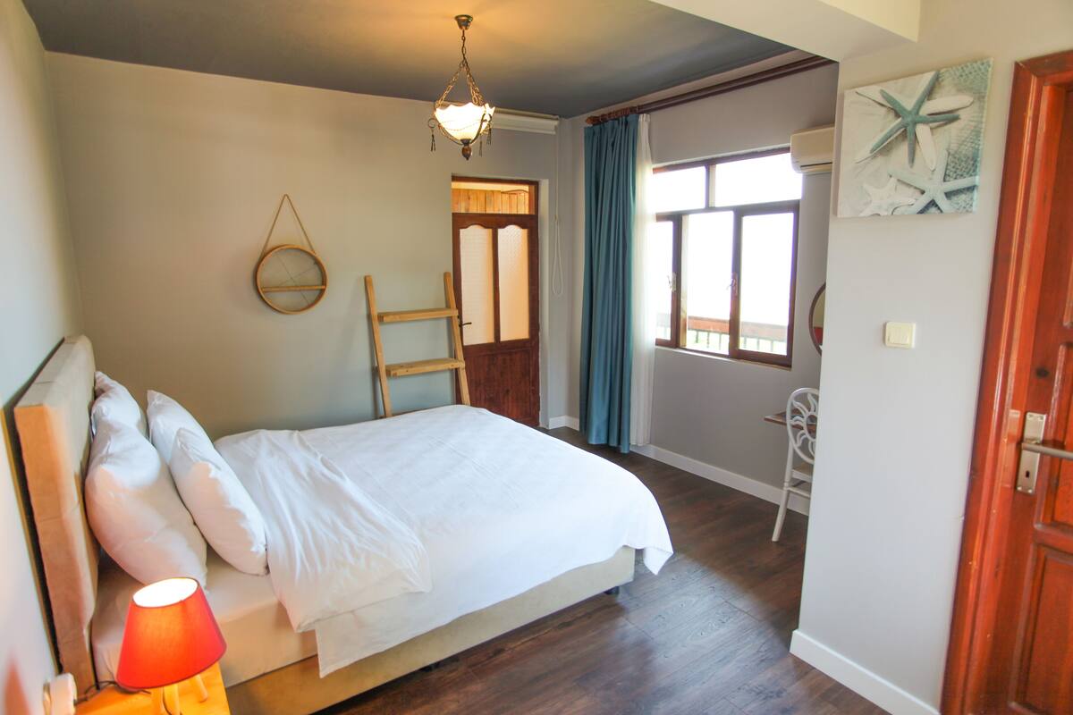 A bedroom with a bed, a chair, a lamp, a window, and a door.