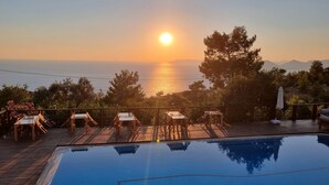 A pool area with lounge chairs and a view of the sunset over the sea. - Faralia Hotel (Fethiye)