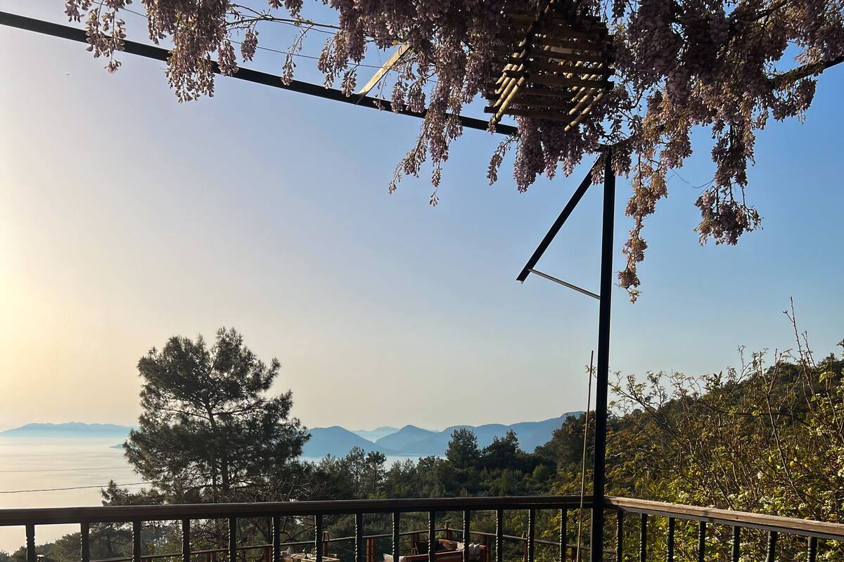 A wooden bench overlooking a pool with a view of the sea and mountains.