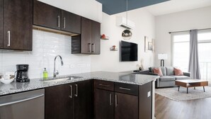 Una cocina moderna con armarios oscuros, encimera de granito y electrodomésticos de acero inoxidable.