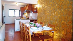 A dining area with a stone wall, wooden table, and chairs. - Casa Azul, Carregal, Óbidos (Óbidos)