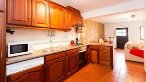 A kitchen with wooden cabinets, a microwave, a sink, and a stove. - Casa Azul, Carregal, Óbidos (Óbidos)