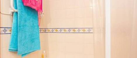 A bathroom with a bathtub, a shower curtain, and two towels hanging on a rack.