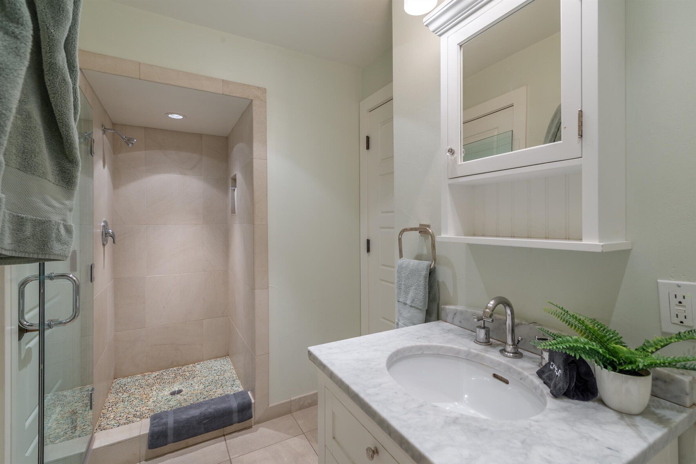 A bathroom with a shower, sink, and mirror.