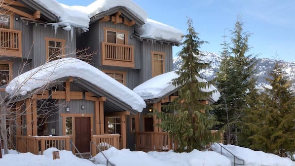 A wooden lodge with a snow-covered roof, wooden balconies, and a snow-covered ground.