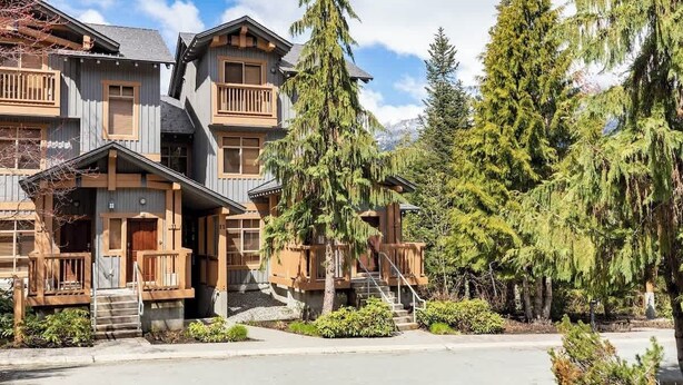 Un lodge de varios pisos con fachada de madera, balcones y un jardín bien cuidado.