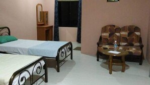 A bedroom with a bed, a small table, a sofa, and a mirror. - Mulu Diana Homestay (Mulu)