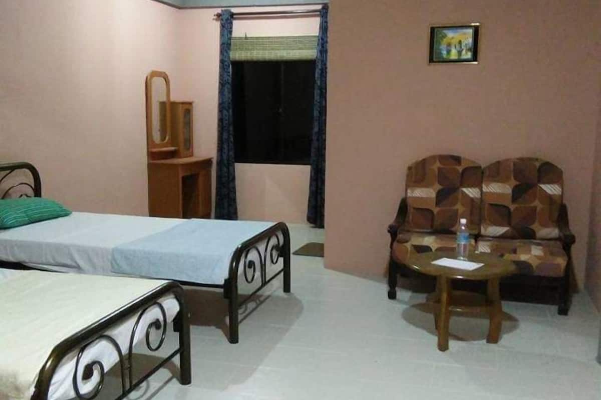 A bedroom with a bed, a small table, a sofa, and a mirror.