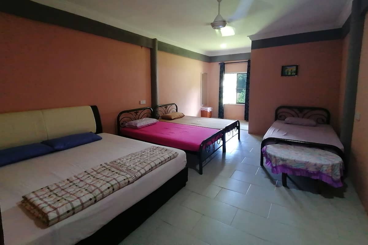 A room with three beds, a ceiling fan, and a window.