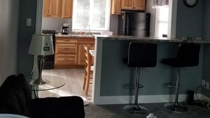 Un ambiente compatto con angolo cottura, zona pranzo e salotto con tavolino in vetro.
